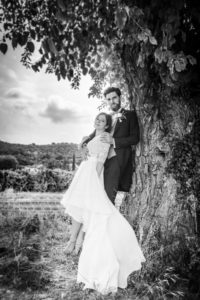 deux jeunes mariés contre un arbre