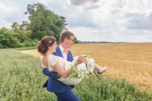 le marié porte la mariée dans un champ de blé