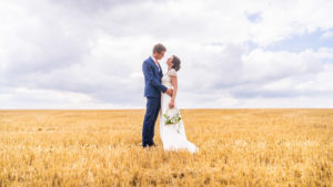 les mariés dans un champ de blé fraîchement coupé