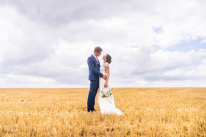 les mariés l'un contre l'autre dans un champs de blé fraîchement coupé