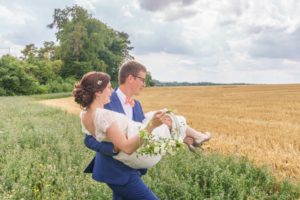 dans les champs, le marié porte la mariée dans ses bras.