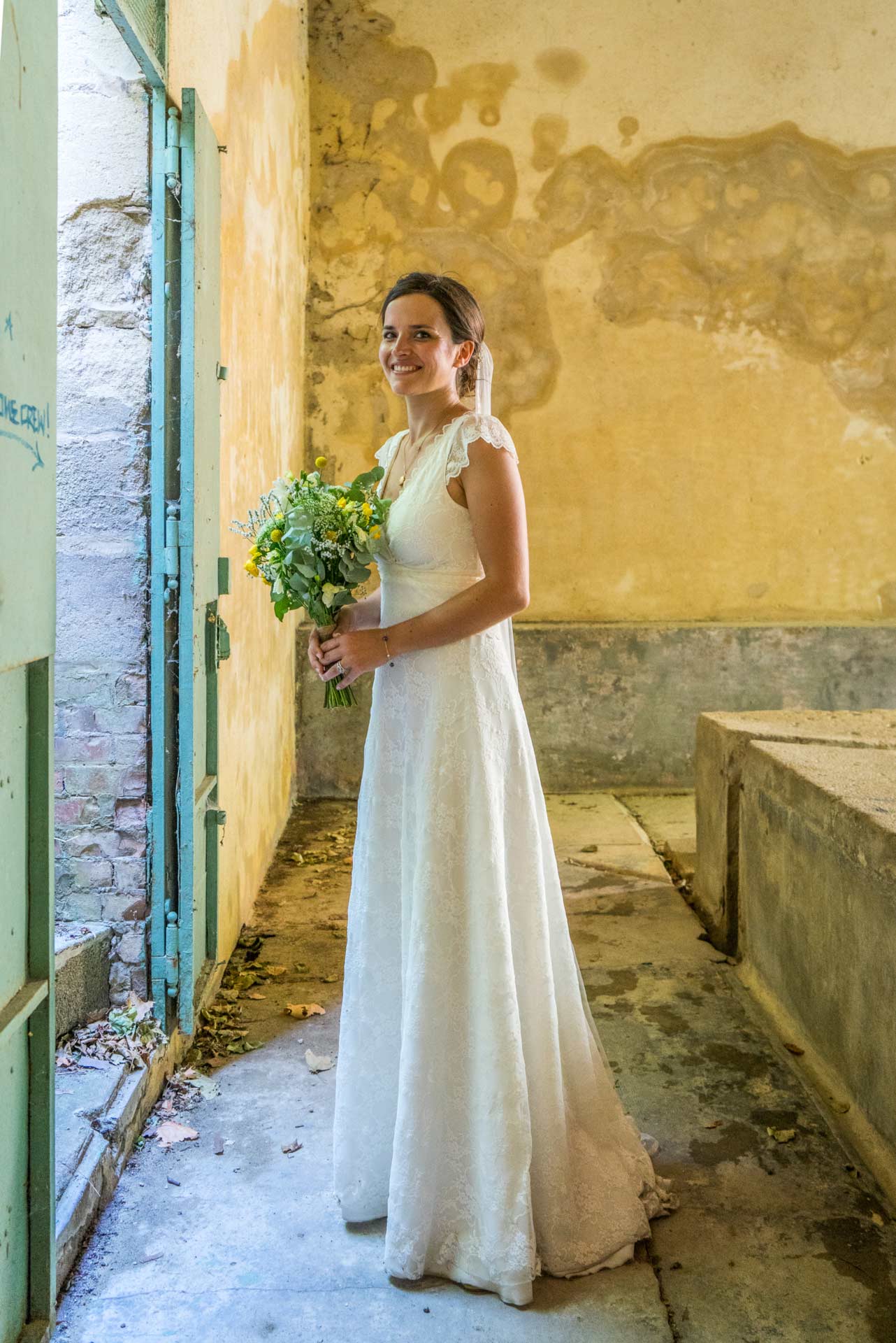 La mariée dans un ancien lavoire, tenant son bouquet.