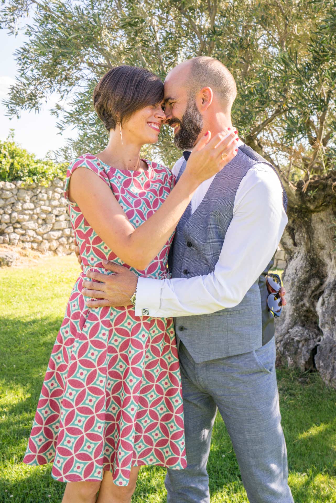 deux amoureux front contre front dans un jardin, sur fond d'olivier et de vieux mur.