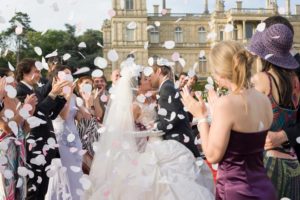 Mariage à Avignon. Les mariés devant un chateau s'embrassent sous une pluie de confettis et les applaudissements de leurs invités. Photographe studio-sud.