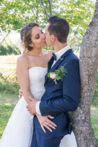 les mariés s'embrassent contre un arbre