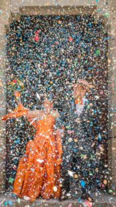 les mariés sortent de l'église sous une pluie dense et multicolore de confettis