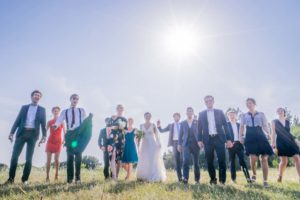 les mariés et leirs invités marchent dans un champ sous le soleil